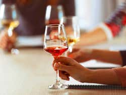 Detalhe das mãos segurando as taças durante a degustaçao de vinho