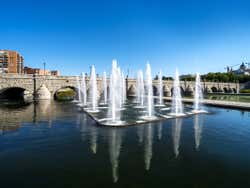 Fontes do Parque Madrid Río com uma ponte de pedra no fundo